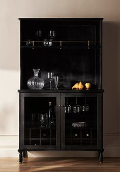 a black china cabinet with glass doors and gold trimmings on the bottom shelf