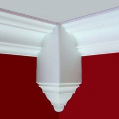 the corner of a room with red walls and white molding on the wall behind it