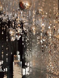 a room filled with lots of shiny balls hanging from it's ceiling next to a mirror