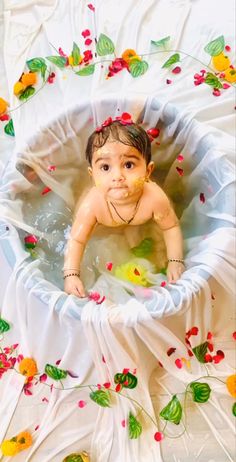 an overhead view of a baby in a bathtub with flowers all over the floor