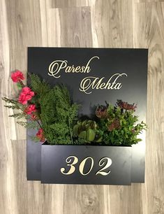 a black sign with flowers and greenery on it