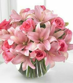 a vase filled with pink flowers sitting on top of a white table next to a window