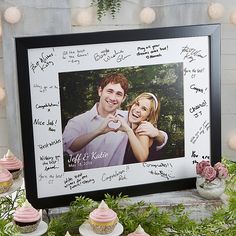 a couple holding a cupcake in front of a cake display with pink frosted cupcakes