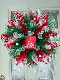 a red and green christmas wreath hanging on the front door with an ornament