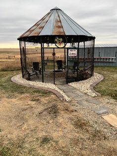 a gazebo sitting on top of a grass covered field next to a dirt road