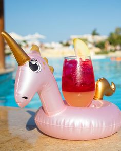 an inflatable unicorn float next to a pool with a drink on it's side