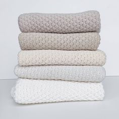 four white blankets stacked on top of each other in different colors and sizes, all folded up