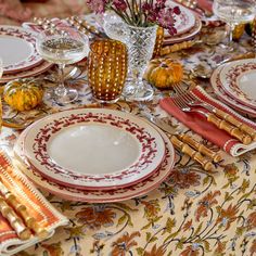 the table is set with plates, silverware and flowers in vases on it