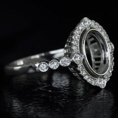 a close up view of a diamond ring on a black surface with the reflection of it