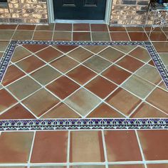 a tile floor with blue and white designs on it in front of a black door