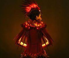 a mannequin dressed in red and gold with feathers