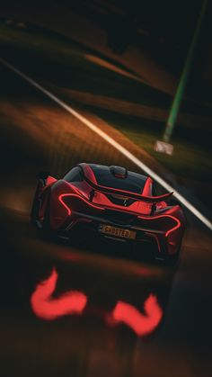 a red sports car driving down the road at night time with lights on it's side