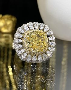 a fancy yellow diamond ring sitting on top of a table next to some gold objects