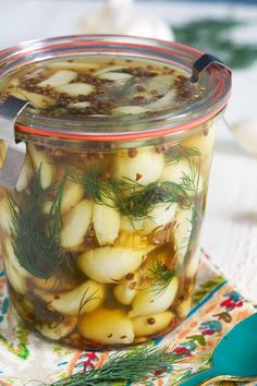 a glass jar filled with pickled onions on top of a table next to a spoon