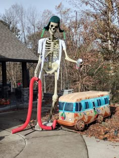 a fake skeleton is standing next to a vw bus with a red hose in it's mouth