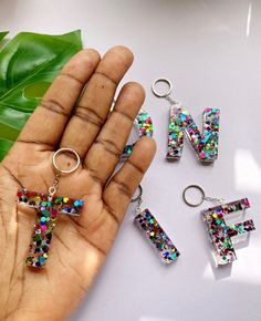 a person holding three different types of keychains in their hand, with the letters n and f on them