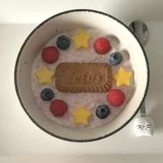 a bowl filled with fruit on top of a white counter next to spoons and utensils