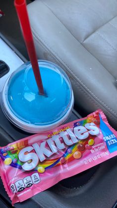 a candy bar sitting in the back seat of a car next to a cup with skittles on it