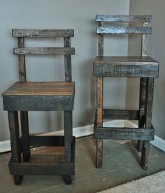 two wooden chairs sitting next to each other on top of a carpeted floor in front of a wall