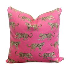 a pink pillow with gold leopards on it sitting on a wooden table next to a white wall