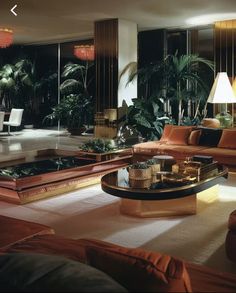 a living room filled with lots of furniture next to tall windows and palm trees in the background