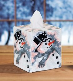 a close up of a tissue box on a table with a snowman and penguin design