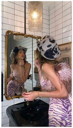 a woman in a zebra print dress is looking at her reflection in the bathroom mirror