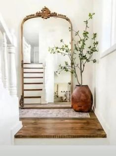 a mirror sitting on top of a wooden table next to a vase with a plant in it