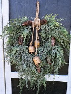 a wreath with pine cones and bells hanging on a door