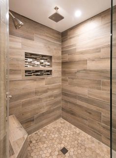 a walk in shower sitting next to a tiled floor and wall with wooden tiles on the walls