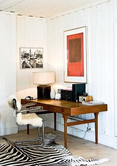 a zebra print rug is in front of a desk with a chair and pictures on the wall