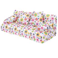 a white couch with colorful flowers on the cover and pillows in front of it, against a white background