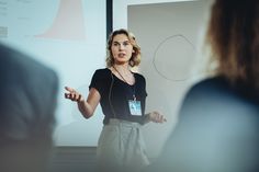 a woman standing in front of a projector screen giving a presentation to her colleagues