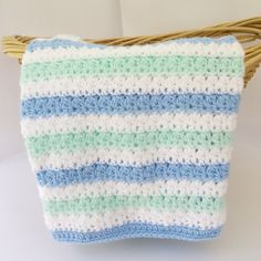 a blue and white crocheted bag hanging from a wicker basket