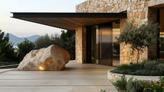 a large rock sitting on the side of a building next to a garden and trees