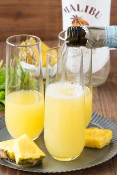 two glasses filled with yellow liquid next to sliced pineapple