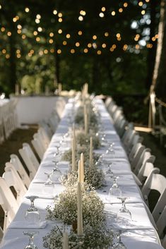 a long table is set with white linens and candles