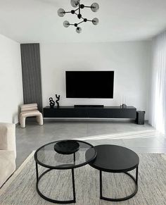 a living room with two black tables and a television on the wall in front of it