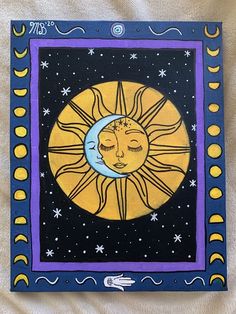 a painting of the sun and moon with stars on it's sides, sitting on a white sheet