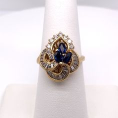 KARAT GOLD: 14K YELLOW GOLD  STYLE: SAPPHIRE & DIAMOND CONTAINS: (3) GENUINE MARQUISE SAPPHIRES (9) ROUND DIAMONDS (28) BAGUETTE DIAMONDS  GEMSTONE WEIGHT: .75CT GEMSTONE MEASUREMENTS: 4.8MM X 2.8MM DIAMOND WEIGHT: .83CT DIAMOND MEASUREMENTS: 2.0MM CLARITY: SI1 COLOR: H TOP OF RING MEASURES: 18.72MM FINGER SIZE: 7 GRAM WEIGHT: 5.4 ALL WEIGHTS ARE APPROXIMATE Gold And Sapphire Jewelry, Gold Marquise Diamond Sapphire Ring, Gold Cluster Sapphire Ring Fine Jewelry, Gold Cluster Sapphire Ring With Prong Setting, Marquise Sapphire Ring With Diamonds In Gold, Fine Jewelry Gold Sapphire Ring For Anniversary, Gold Sapphire Ring For Anniversary, Gold Marquise Sapphire Ring In 14k Gold, Fine Jewelry Gold Marquise Sapphire Ring