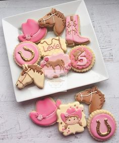 decorated cookies on a white plate with pink and brown decorations for horse themed birthdays