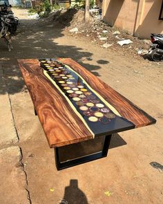 a table made out of wood and glass on the side of a dirt road next to a motorcycle