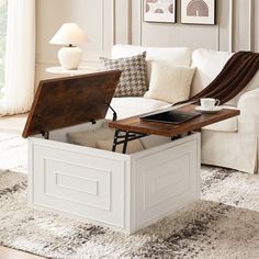 a living room with a white couch and coffee table on top of it, in front of a window