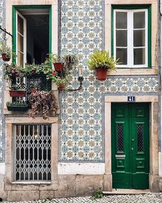 a green door and window in front of a building with flowers on the windowsill