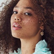 a woman with freckles on her face looking off to the side while wearing earrings