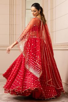 Red asymmetric organza brocade lehenga with an under-layer of chevron borders. Paired with a textured bustier with fringe embellishment. Comes with a sheer cape with square-cut gota embroidery and gota-lined wings extended in the back.
Component: 3
Pattern: Embroidered
Type Of Work: Geometric
Neckline: Cape: Round
Sleeve Type: Cape: Draped Sleeves
Fabric: Silk organza brocade
Color: Red
Other Details: 
Draped lehenga
Tassel detail
Gota work
Asymmetric cape
Occasion: Destination Wedding - Aza Fas Red Sharara With Sheer Dupatta In Chanderi, Red Chanderi Dress With Sheer Dupatta, Red Dresses With Gota Work In Traditional Drape, Celebration Red Sharara With Cutdana, Red Organza Floor-length Saree, Floor-length Red Organza Saree, Red Gota Work Choli For Reception, Red Floor-length Lehenga With Gota Work, Red Georgette Lehenga With Cutdana