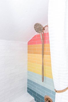 there is a shower in the bathroom with rainbow tiles on the walls and flooring