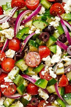 a salad with cucumbers, tomatoes, onions, olives and feta cheese