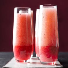 two glasses filled with red liquid sitting on top of a white napkin next to each other