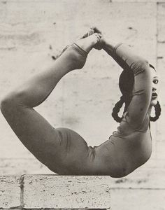 an old black and white photo of a woman doing yoga exercises with her hands behind her head